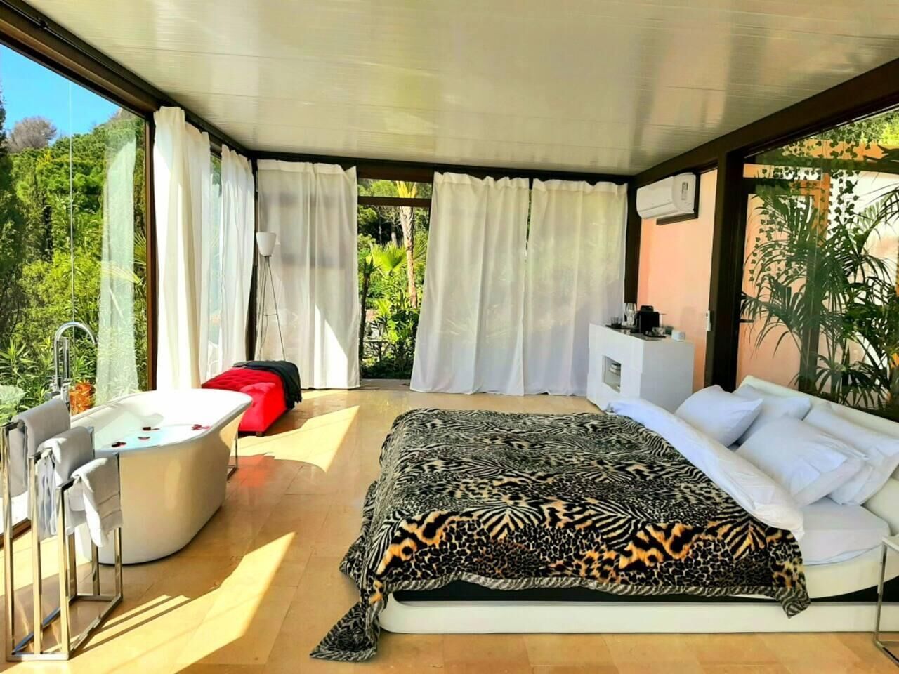Un dormitorio moderno con una cama grande, una bañera y vistas a zonas verdes.