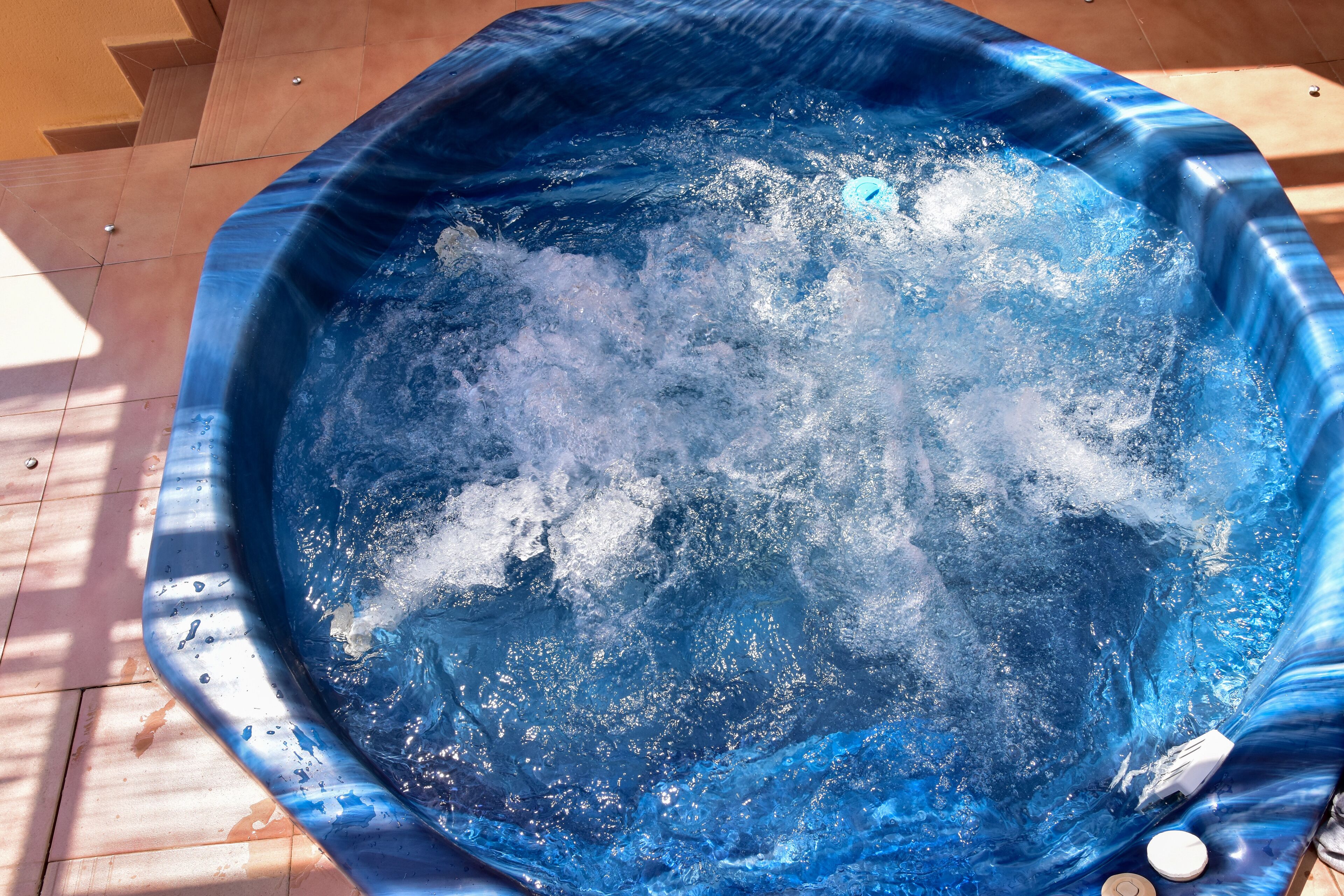 A hot tub with water bubbling, surrounded by wooden decking.