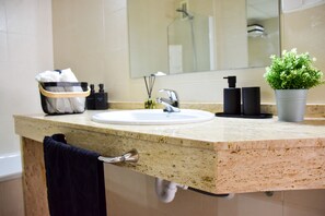 A bathroom with a sink, mirror, towel rack, and a potted plant.
