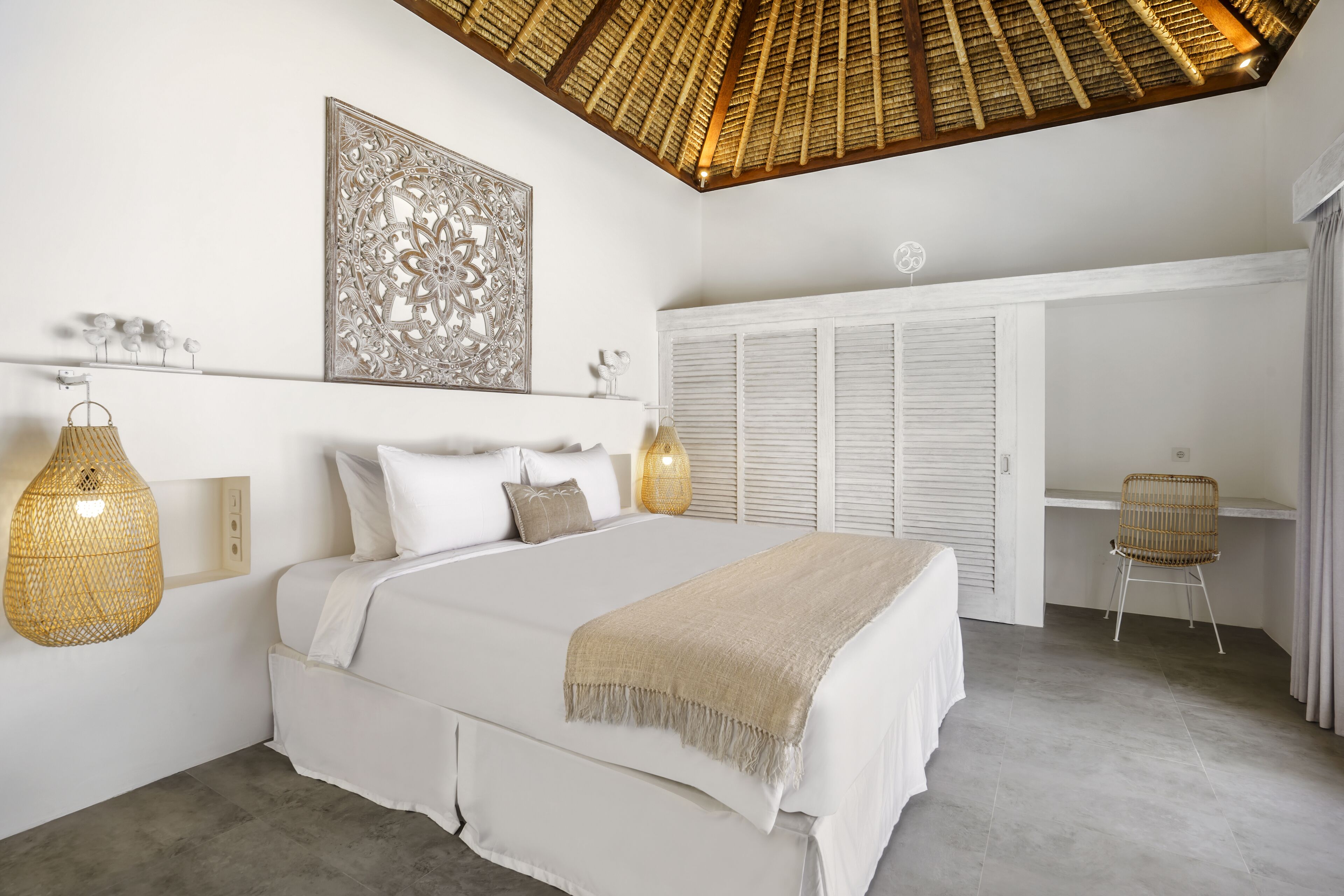 A bedroom with a large bed, a ceiling fan, a decorative wall piece, and a wardrobe.