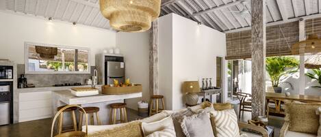A modern kitchen with a central island, bar stools, and a dining area with a table and chairs.