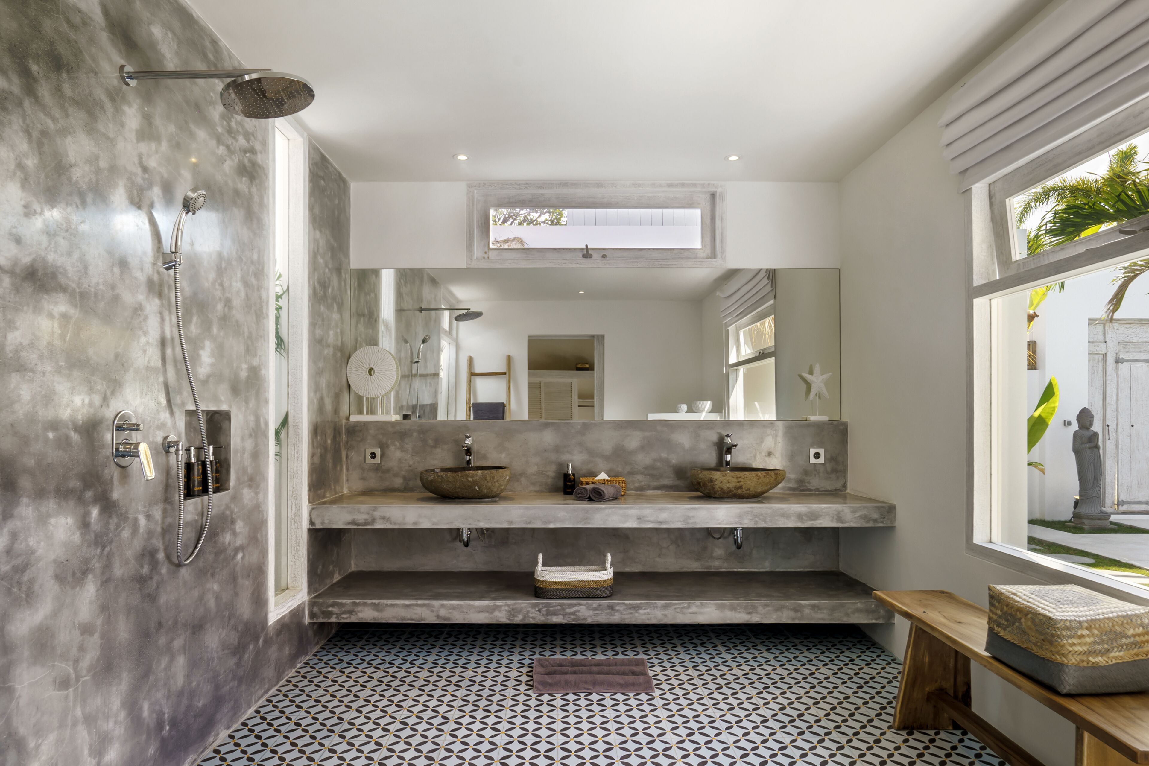A modern bathroom with a large mirror, two sinks, a shower, and a window with a view of the outside.