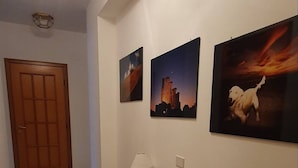 A hallway with a wooden door, a white cabinet with a blue top, and three framed pictures on the wall. - Relax at the Valley of the Temples (Agrigento)