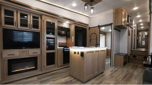 Een moderne keuken met houten kastjes, een inbouwoven, een magnetron, en een centraal eiland met een spoelbak.