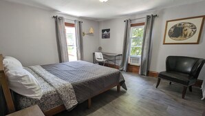 A bedroom with a bed, a chair, a desk, and a picture on the wall.
