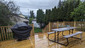 A wooden deck with a picnic table and grill.