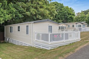 Une rangée de maisons mobiles avec des garde-corps blancs et une pelouse.