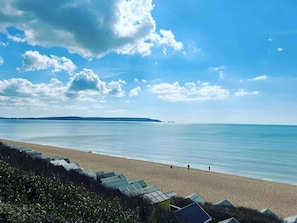 Une plage avec un ciel dégagé, une mer calme et une côte lointaine.