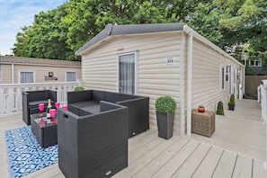 Une maison mobile dotée d’un patio aménagé avec des meubles d’extérieur et des jardinières.