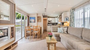 Ein modernes Wohnzimmer mit einer Couch, einem Essbereich mit Stühlen, einer Küche mit Schränken und einem Kamin.