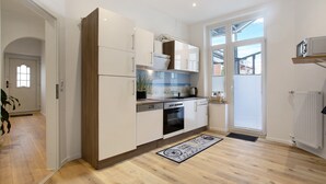 Eine moderne Küche mit weißen Schränken, einem eingebauten Backofen und einem Fenster mit Jalousien.