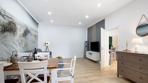Ein modernes Wohnzimmer mit Essbereich, einem Fernseher und einem großen abstrakten Gemälde an der Wand.