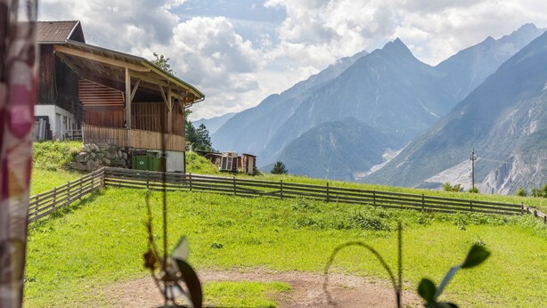 Vista de la montaña con un edificio de madera y un área cercada.