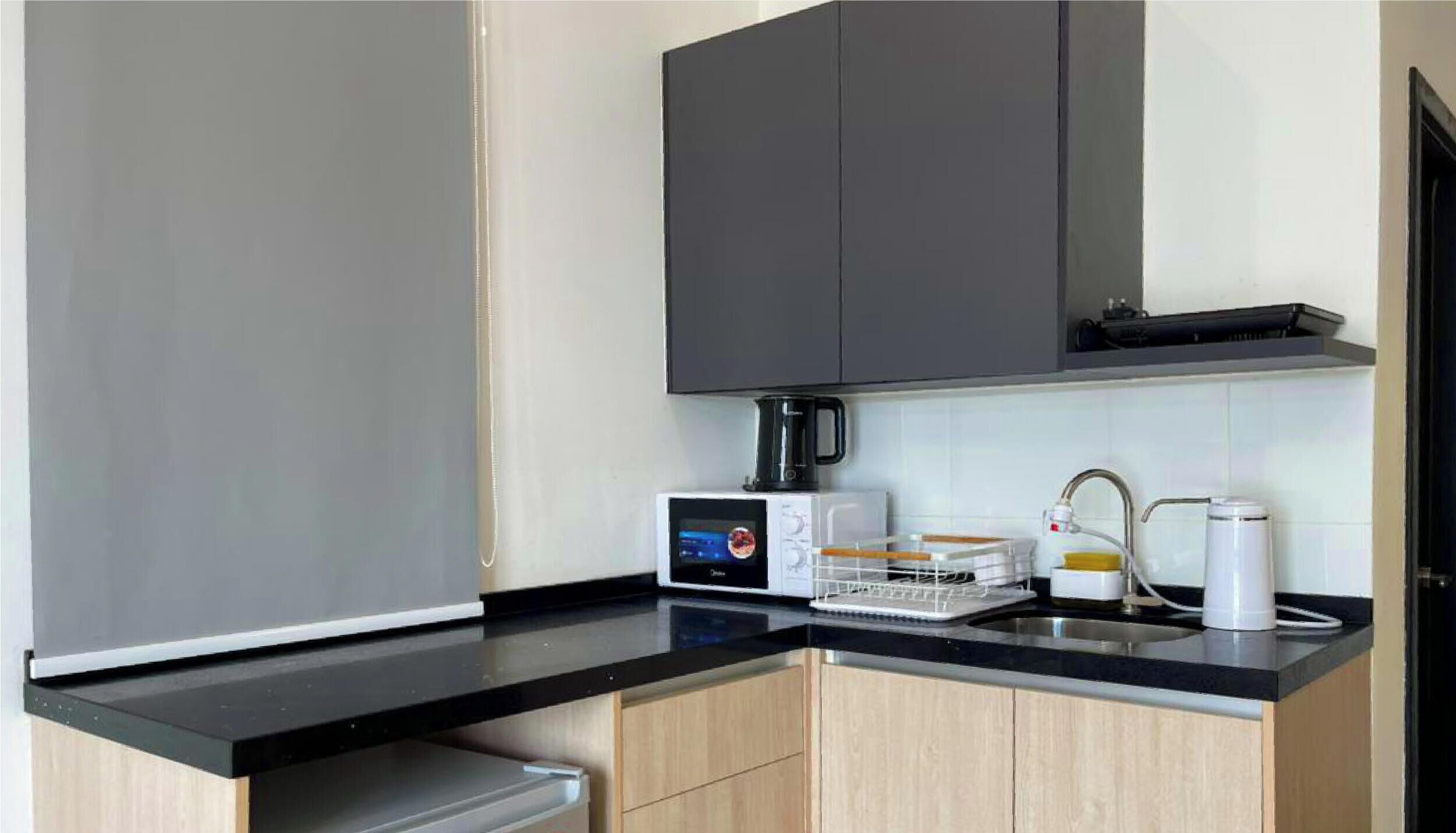 A compact kitchen with a black countertop, a coffee maker, a microwave, and a sink.