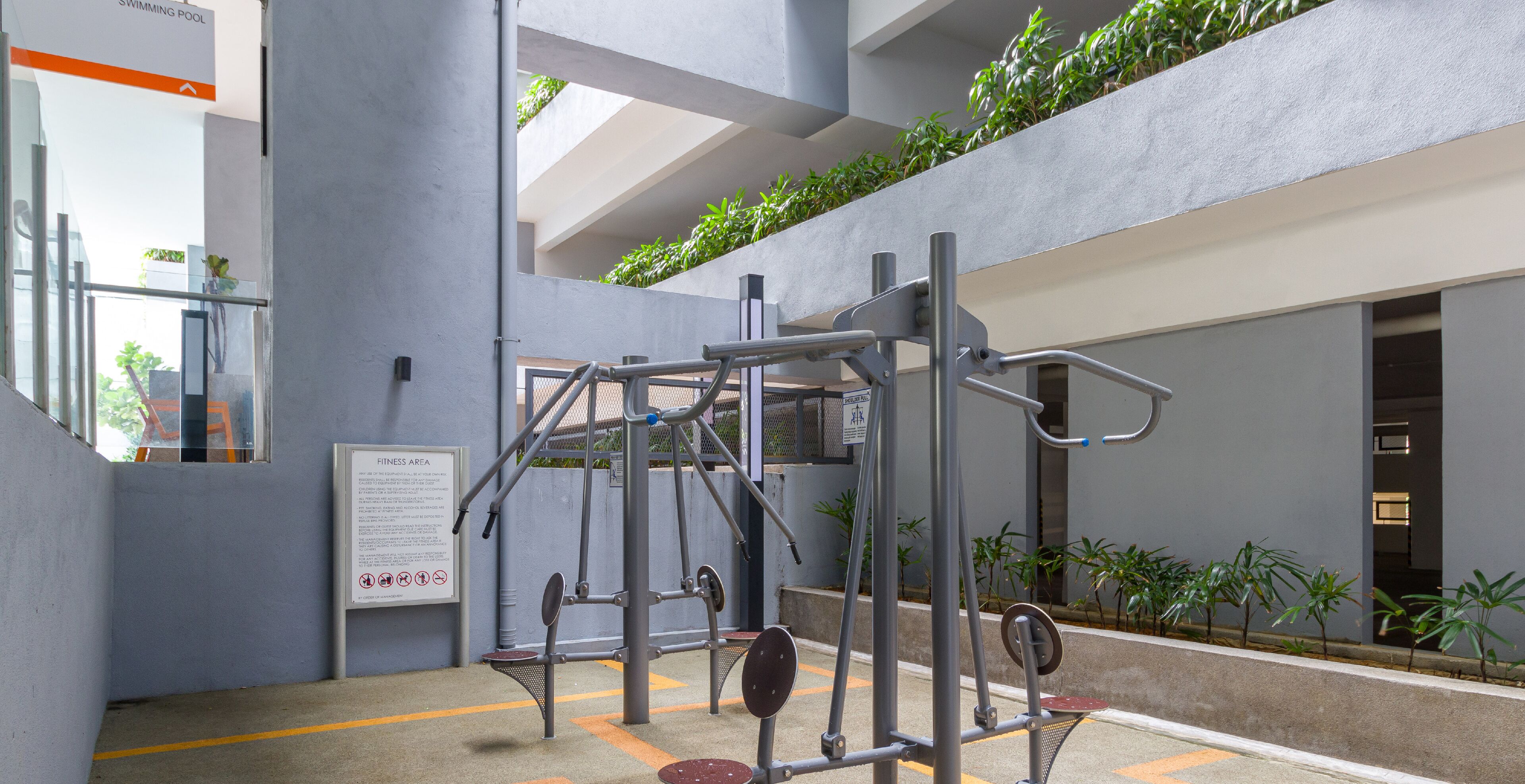 An indoor gym with exercise equipment, a sign indicating a no smoking area, and a view of a swimming pool through a glass door.