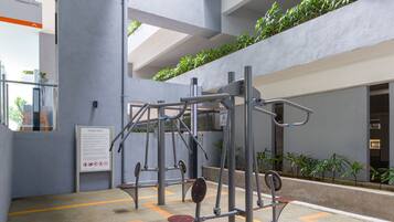 An indoor gym with exercise equipment, a sign indicating a no smoking area, and a view of a swimming pool through a glass door.