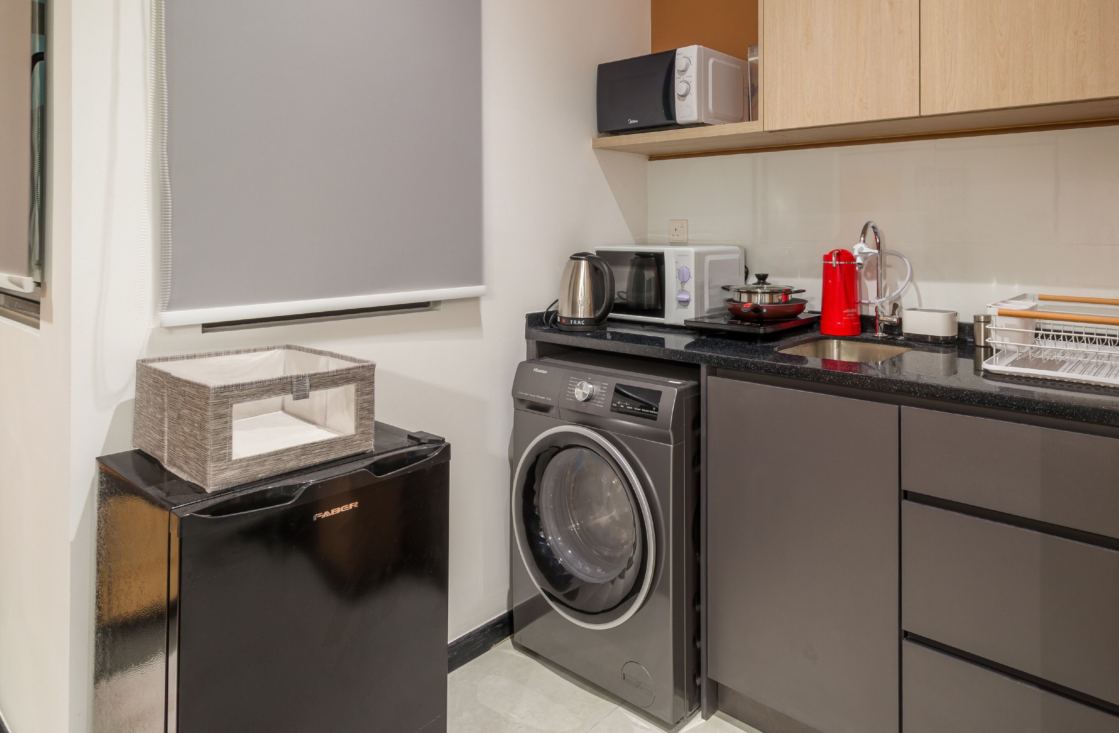 A compact kitchen with a washing machine, a microwave, and a coffee maker.