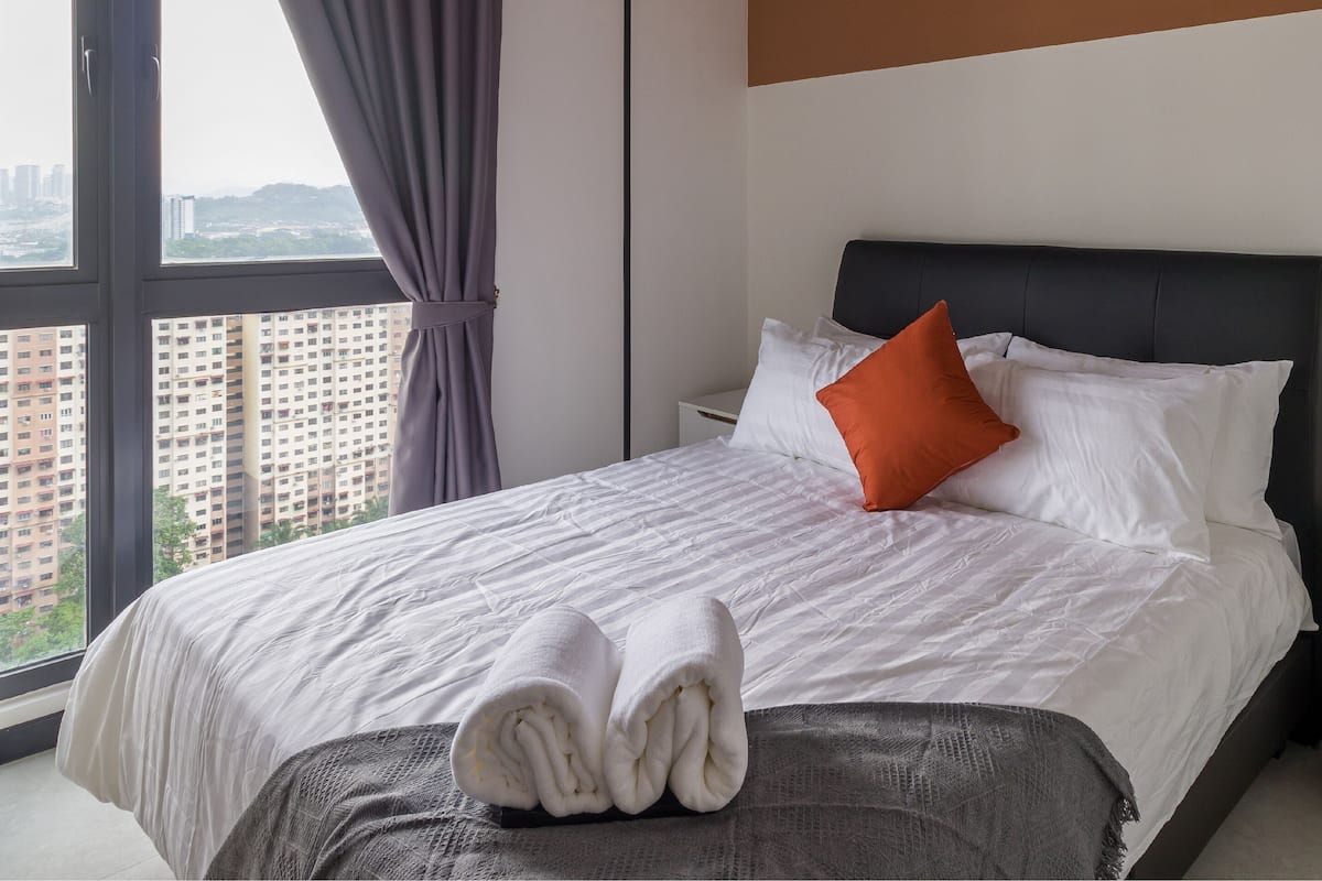 Ein Hotelzimmer mit Bett, Nachttisch und Blick auf hohe Gebäude.