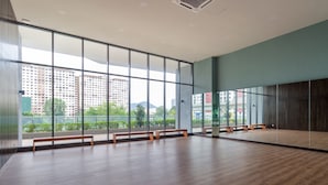 Una habitación amplia con ventanas grandes, suelo de madera y bancos a lo largo de las paredes.