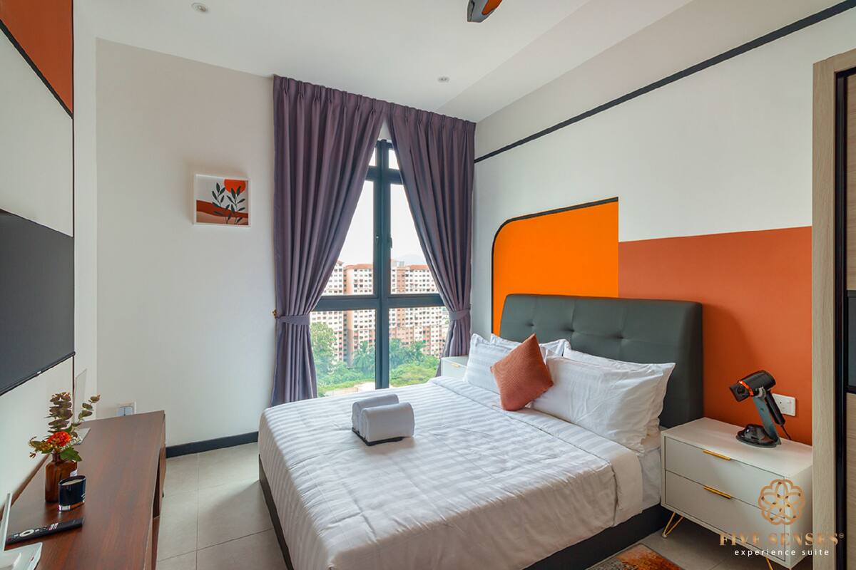 Ein modernes Hotelzimmer mit einem großen Bett, einem Nachttisch, einem Schreibtisch und einem Fenster mit Vorhängen.