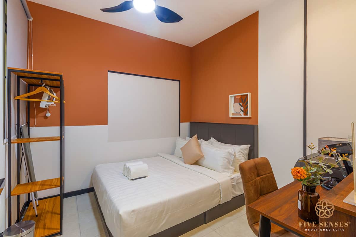 Ein Hotelzimmer mit Bett, Schreibtisch, Stuhl, Kleiderschrank und Deckenventilator.