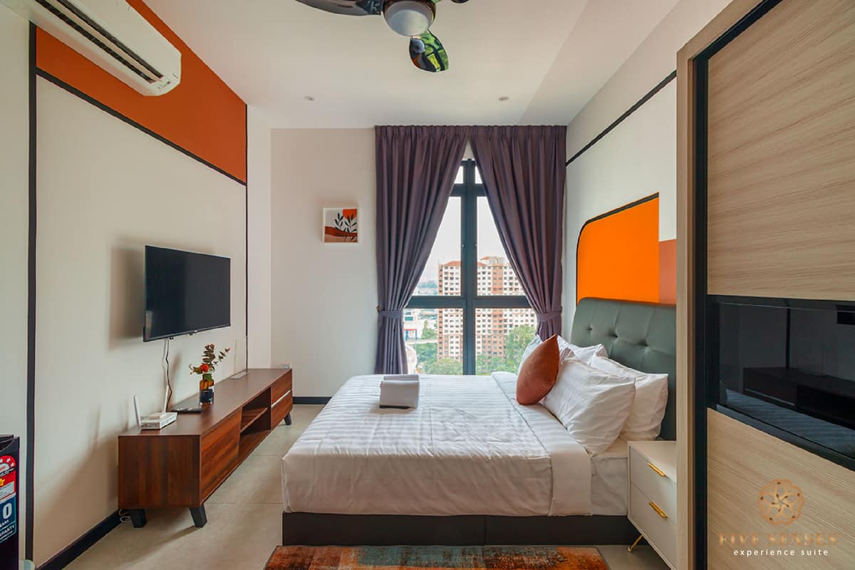 Ein modernes Hotelzimmer mit Bett, Fernseher, Schreibtisch und einem fensterbepflanzten Fenster.