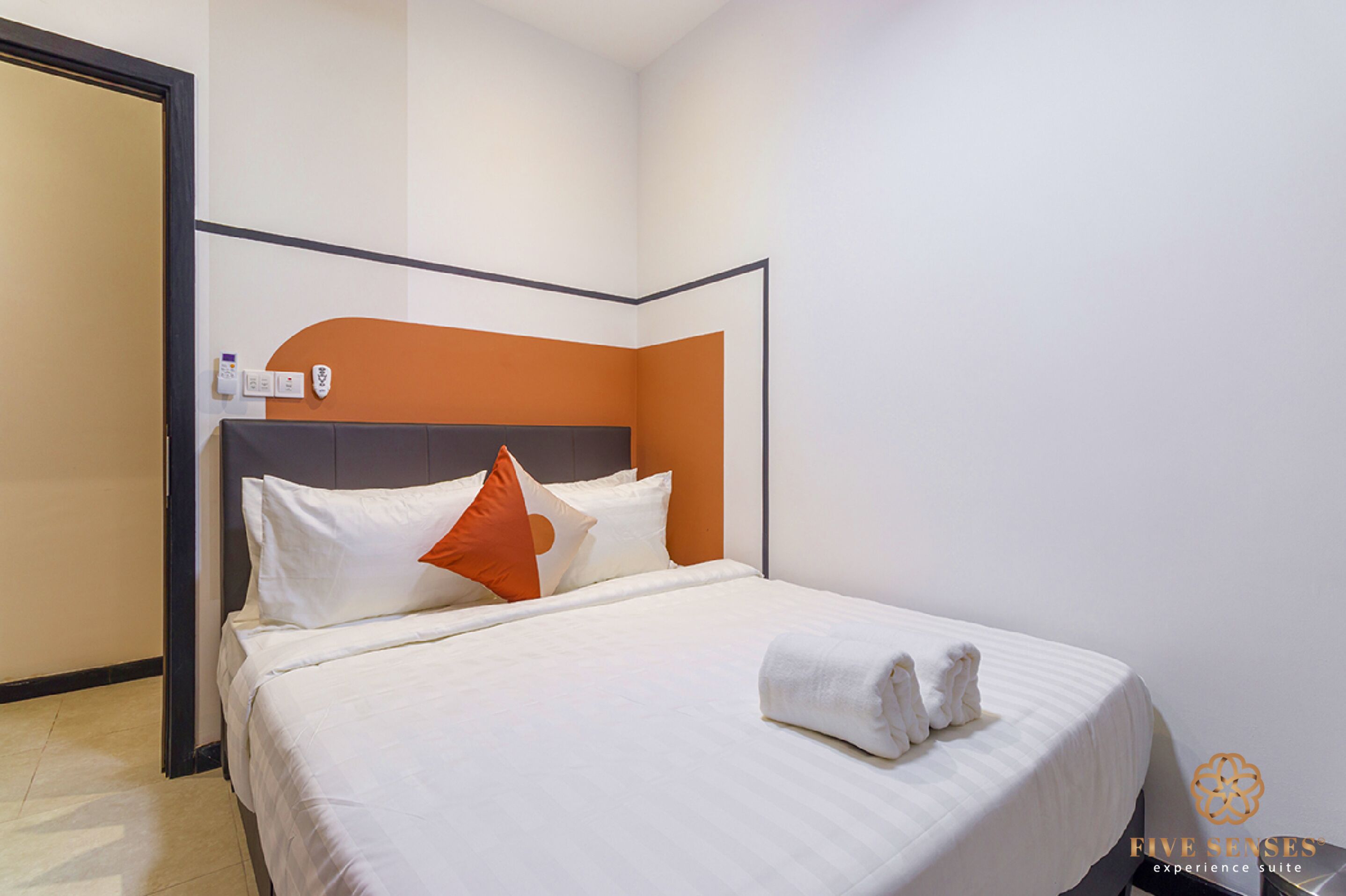 A hotel room with a bed, pillows, a headboard, and a towel on the bed.