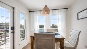 A dining area with a wooden table, white chairs, and a hanging pendant light.