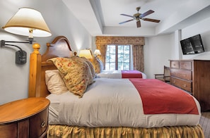 Relax in comfort with a large bed, flat-screen TV, and a wooden nightstand.