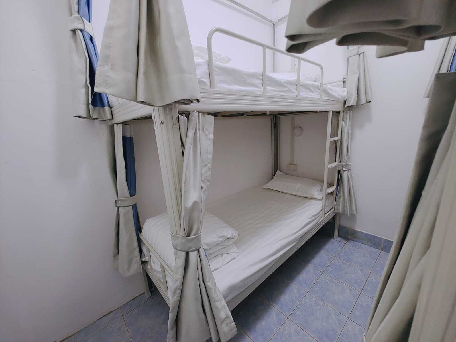 A bunk bed room with a white mattress, metal railings, and a curtain.