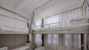 Un dormitorio con literas, una mesa azul y cortinas.