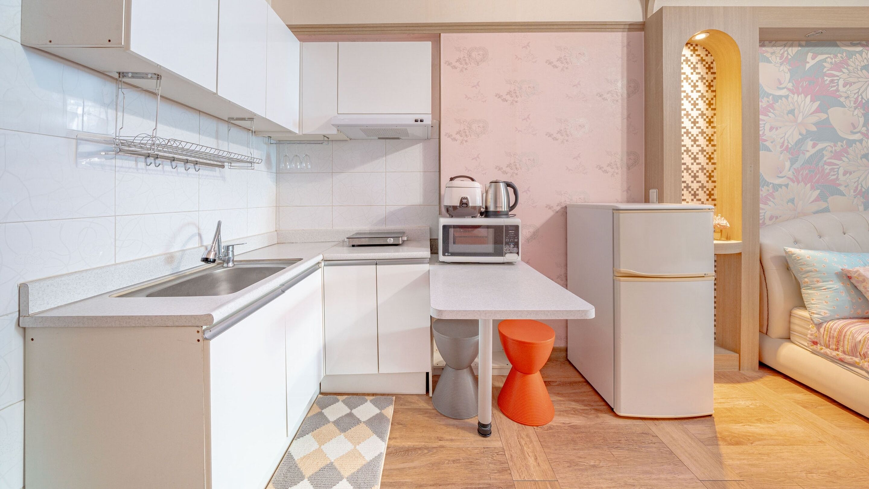 A compact kitchen with white cabinets, a microwave, a kettle, and a refrigerator.