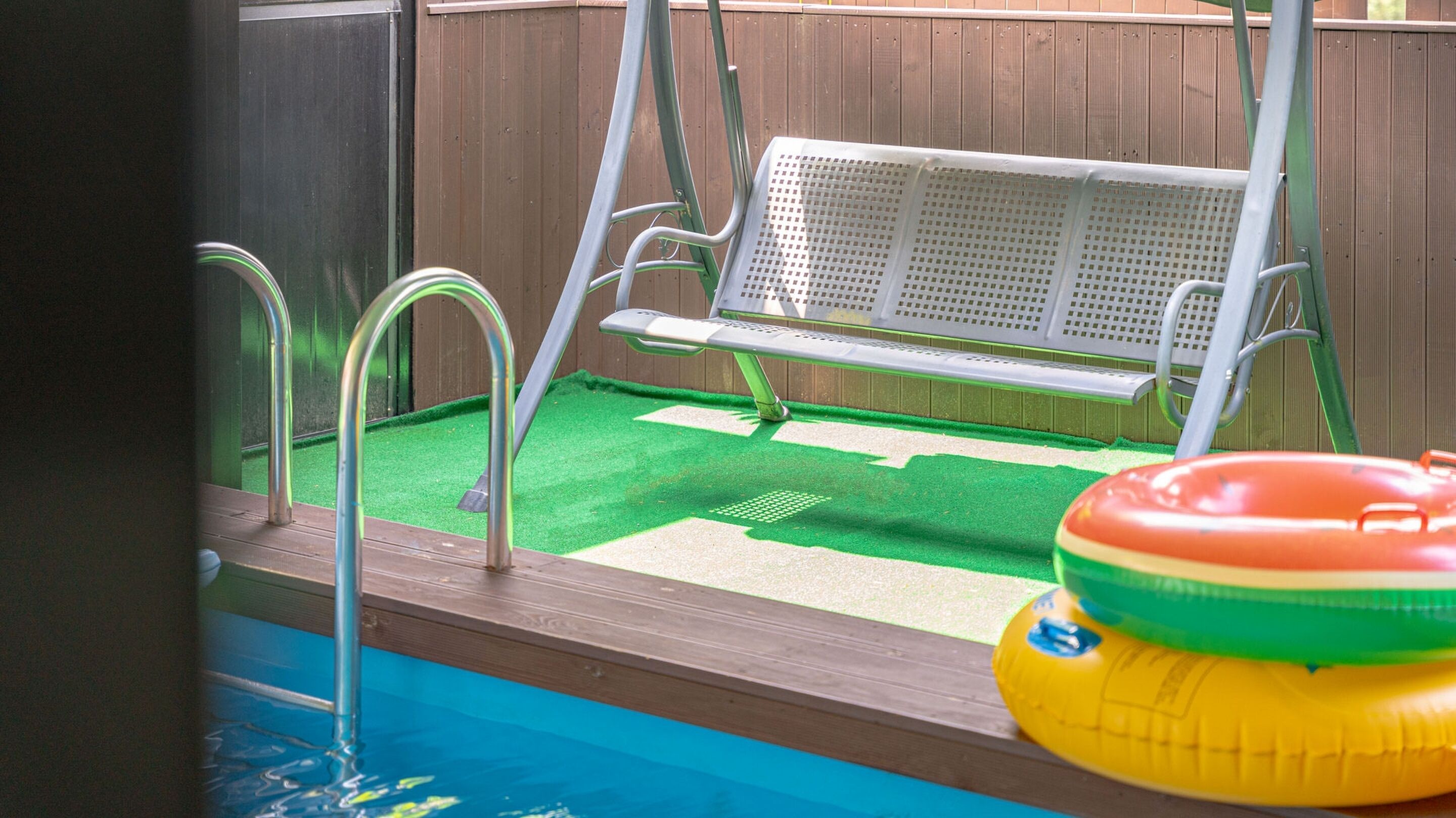 A pool with a swing chair and a floating ring.