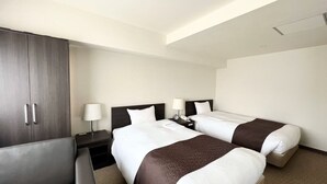 Une chambre d’hôtel avec deux lits, une armoire, un bureau et une chaise.