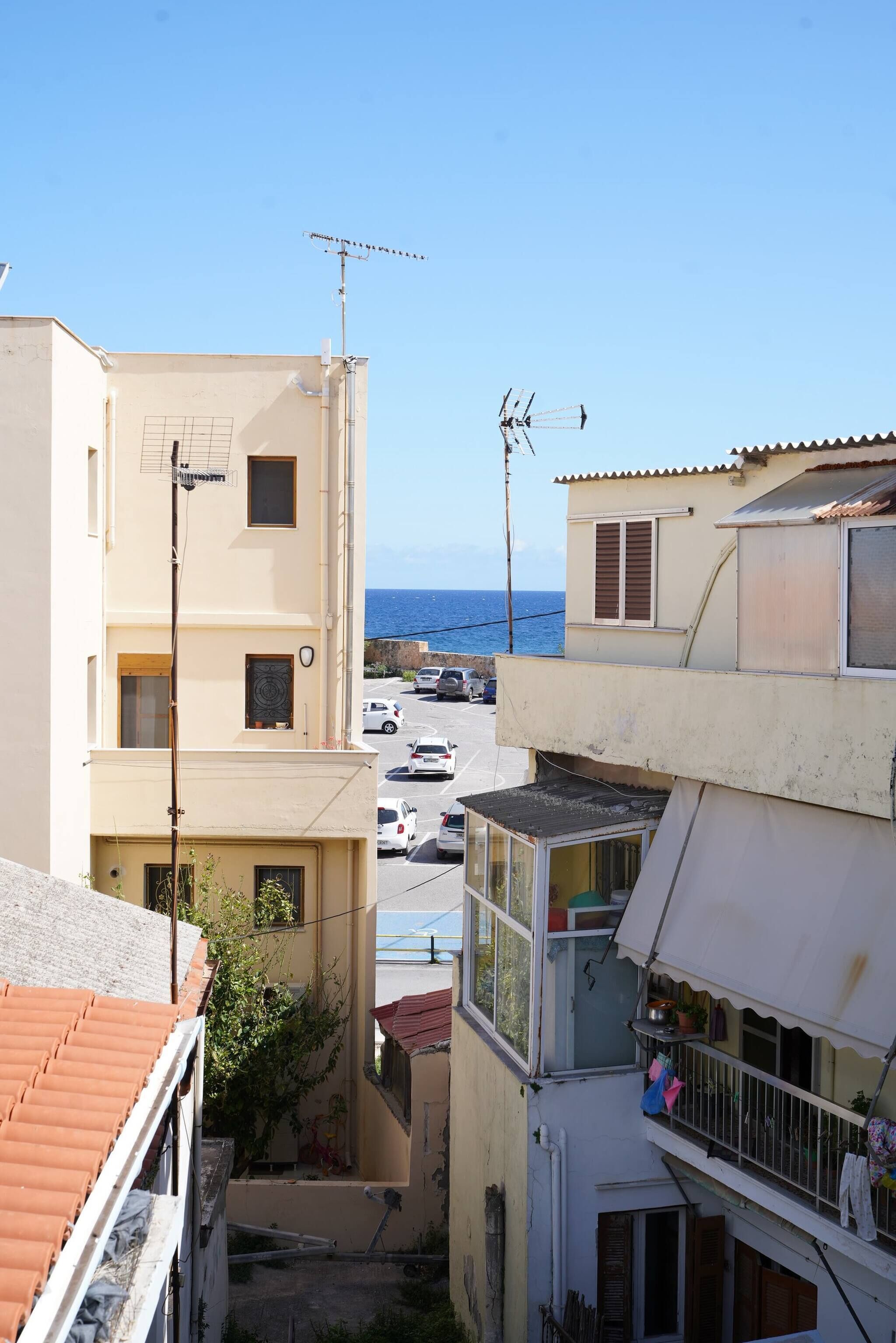 A residential area with buildings, a street, and a view of the sea.