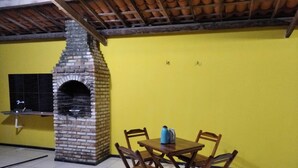A room with a brick oven, yellow walls, and a tiled floor. - Casa em Paracuru Beach (Paracuru)