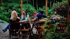 Un grupo de personas sentadas en una mesa de madera al aire libre, rodeadas de abundante vegetación.