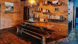 Um interior rústico com vigas de madeira aparente, parede de tijolos e um banco de madeira.