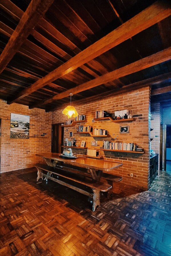 Un interior rústico con vigas de madera a la vista, una pared de ladrillo y un banco de madera.