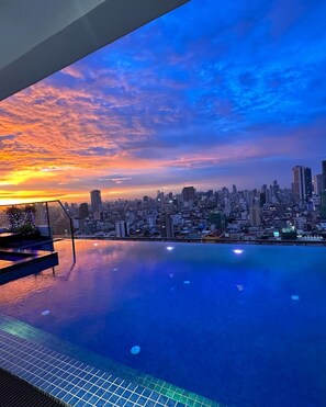 An infinity pool with a city skyline view at sunset.