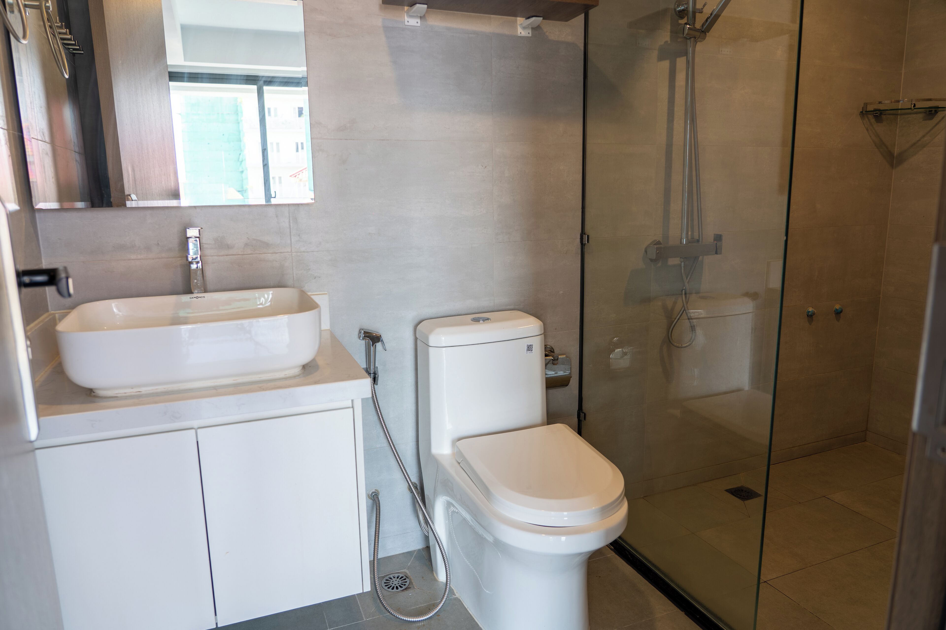 Une salle de bain moderne avec une douche à parois de verre, un lavabo blanc et des toilettes.
