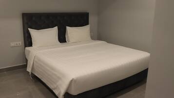 A neatly made bed with a dark headboard and white bedding in a modern room with a tiled floor.