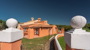 Ein traditionelles Haus im mediterranen Stil mit Terrakotta-Dächern, einem Steinweg und weißen, kugelförmigen Verzierungen an den Wänden.