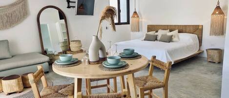 Une pièce comprenant un lit, une table ronde en bois avec des chaises, un canapé et un grand miroir.