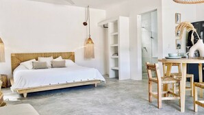 A bedroom with a wooden bed, a hanging lamp, and a dining area with wooden chairs and a table. - Cozy Studio In La Veleta (Tulum)
