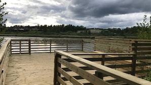 A wooden boardwalk leading to a riverbank with a cloudy sky above. - Bjurvik's Villa - Flat 2 - Business Customers Only (Flen)