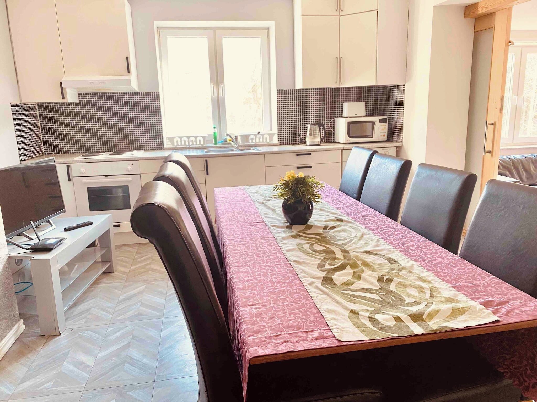 A modern kitchen with white cabinets, a microwave, and a dining area with a table set for four.