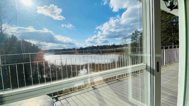 A deck with a glass railing overlooking a frozen lake and trees. - Bjurvik's Villa - Flat 2 - Business Customers Only (Flen)