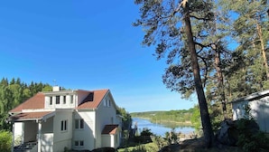 A two-story house with a red-tiled roof, a balcony, and a view of a lake. - Bjurvik's Villa - Flat 2 - Business Customers Only (Flen)