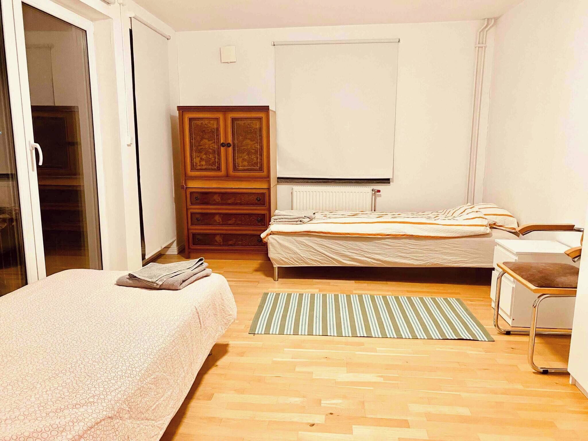 A bedroom with a bed, a wardrobe, a radiator, and a window.